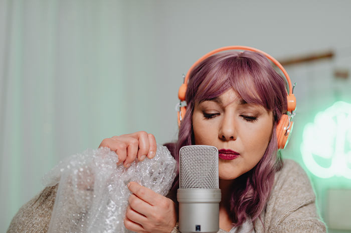 mujer grabando sonidos de burbujas de plástico