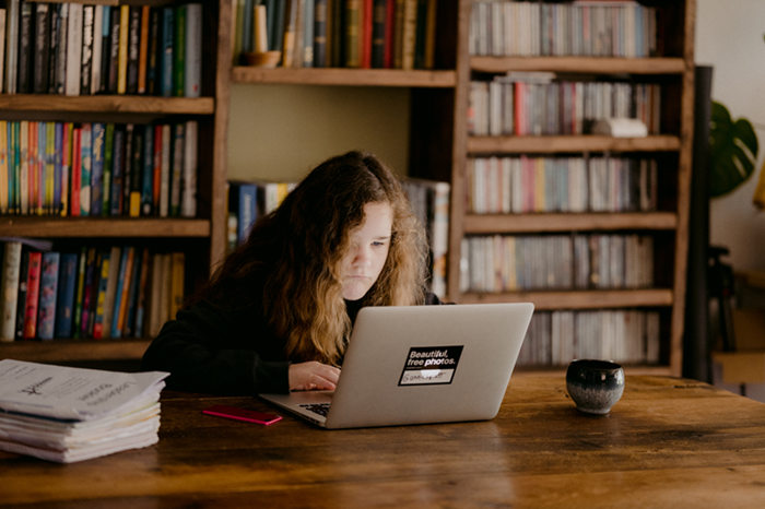 girl reading on a laptop in a library 