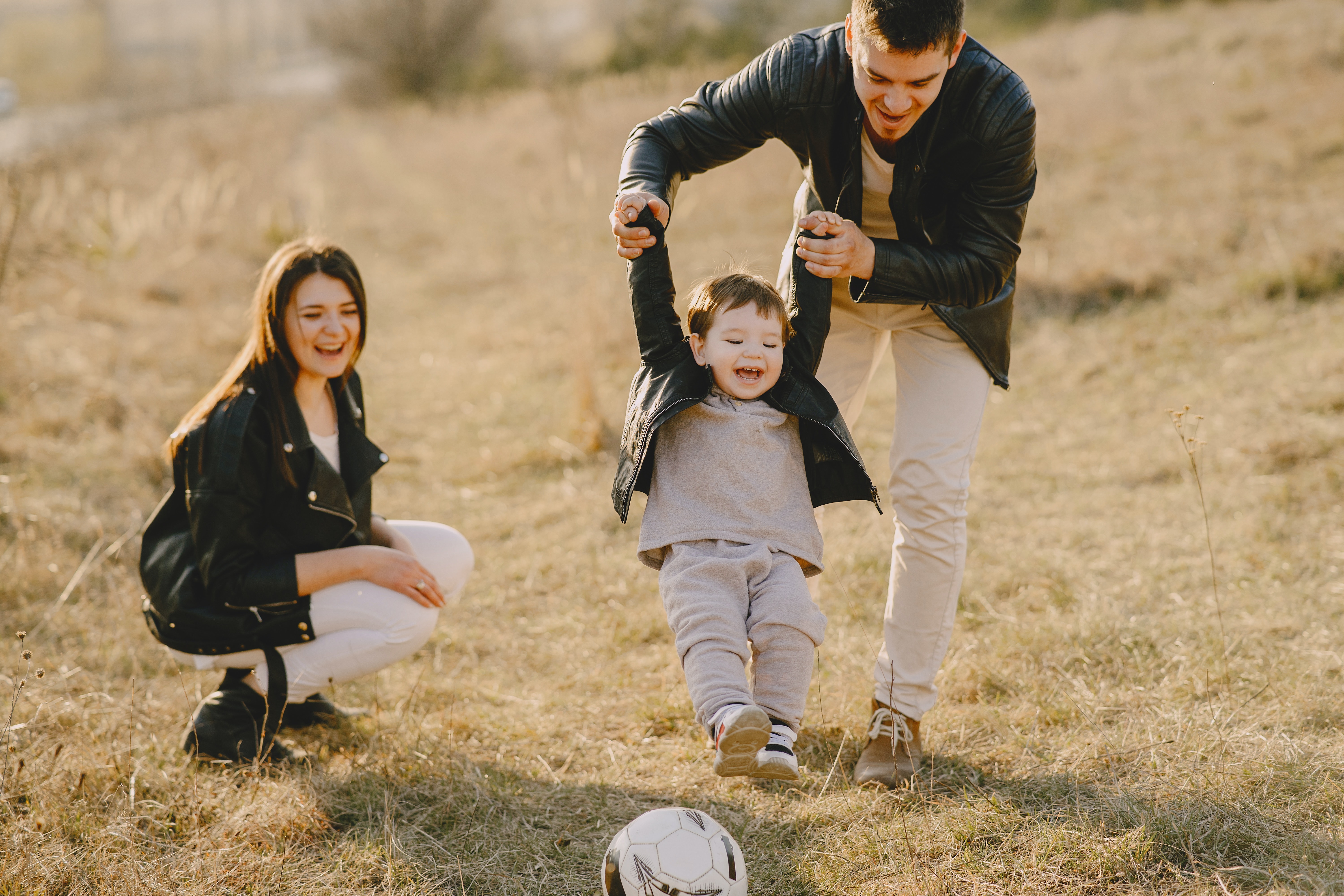 parents playing with child in the field 