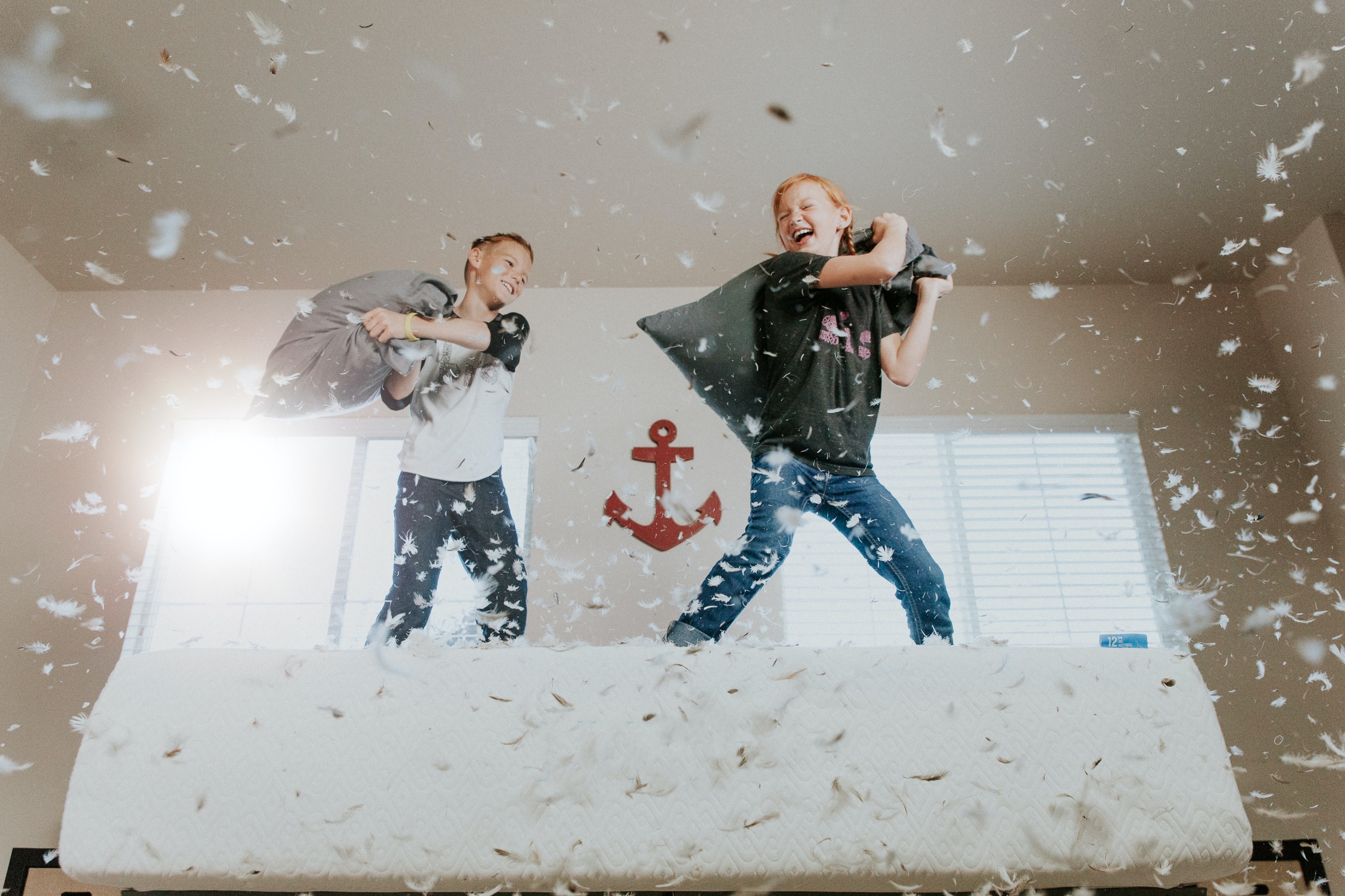 kids pillow fighting on bed 