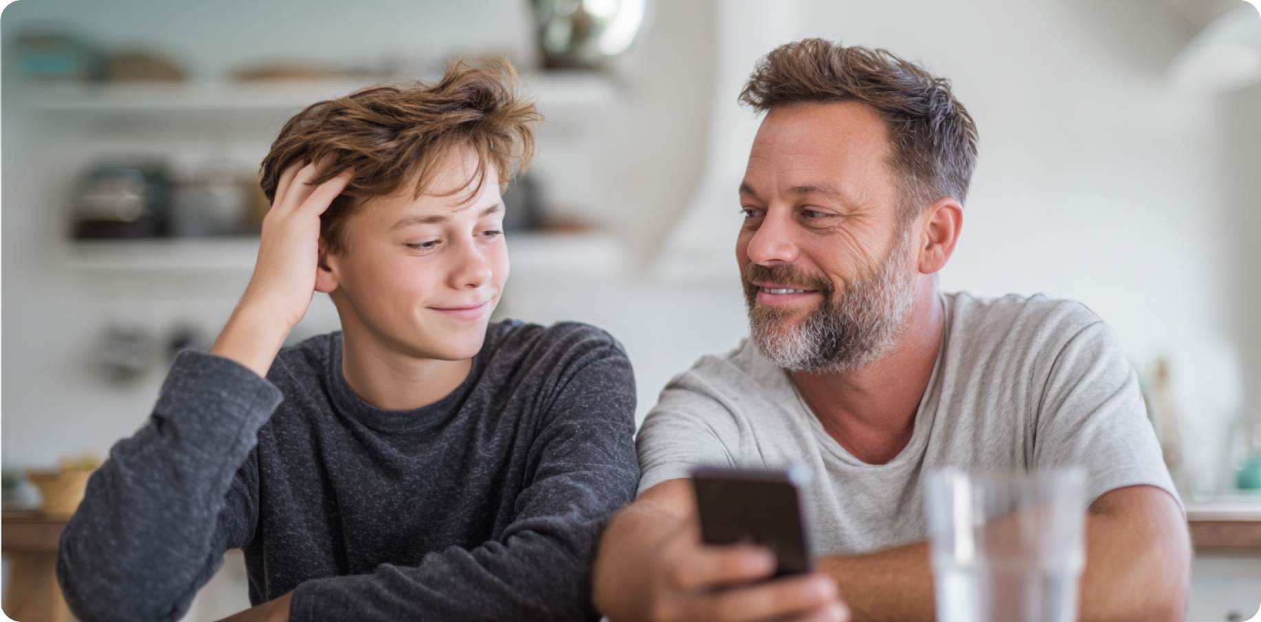 Father showing phone at dinner table during school discussion
